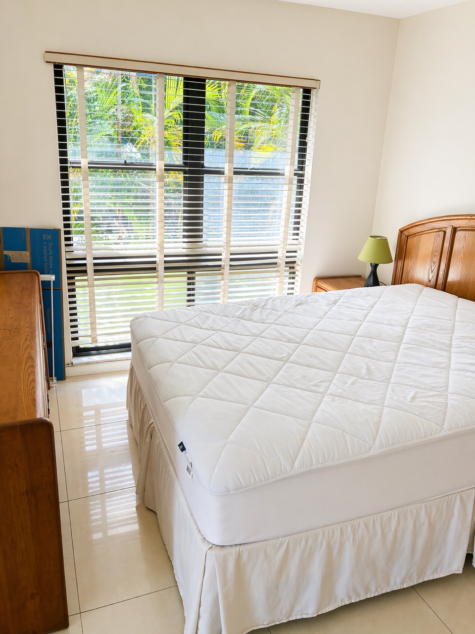 Clean bedroom with bright window, made bed, and polished tile floor