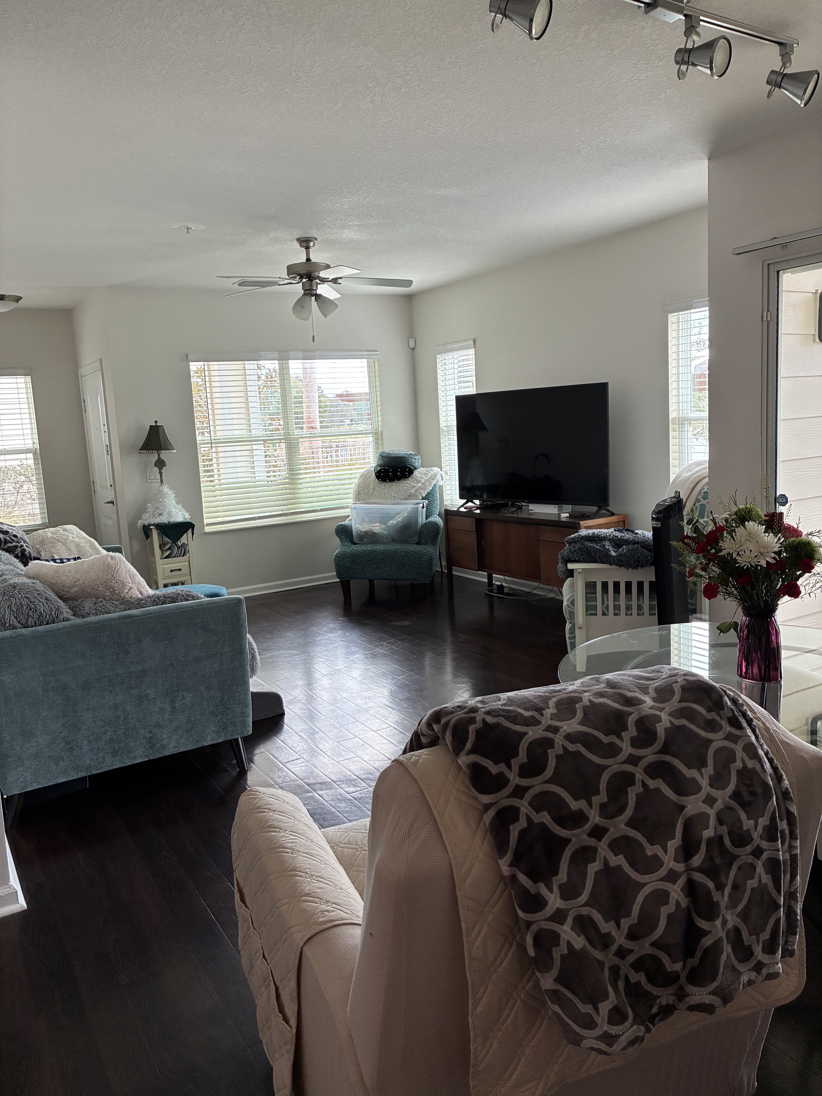 Clean furnished living room with dark floors, windows, and seating