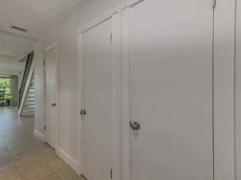 Clean hallway with white doors and tile flooring