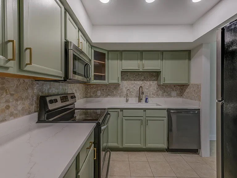 Clean kitchen with sage cabinets and stainless appliances