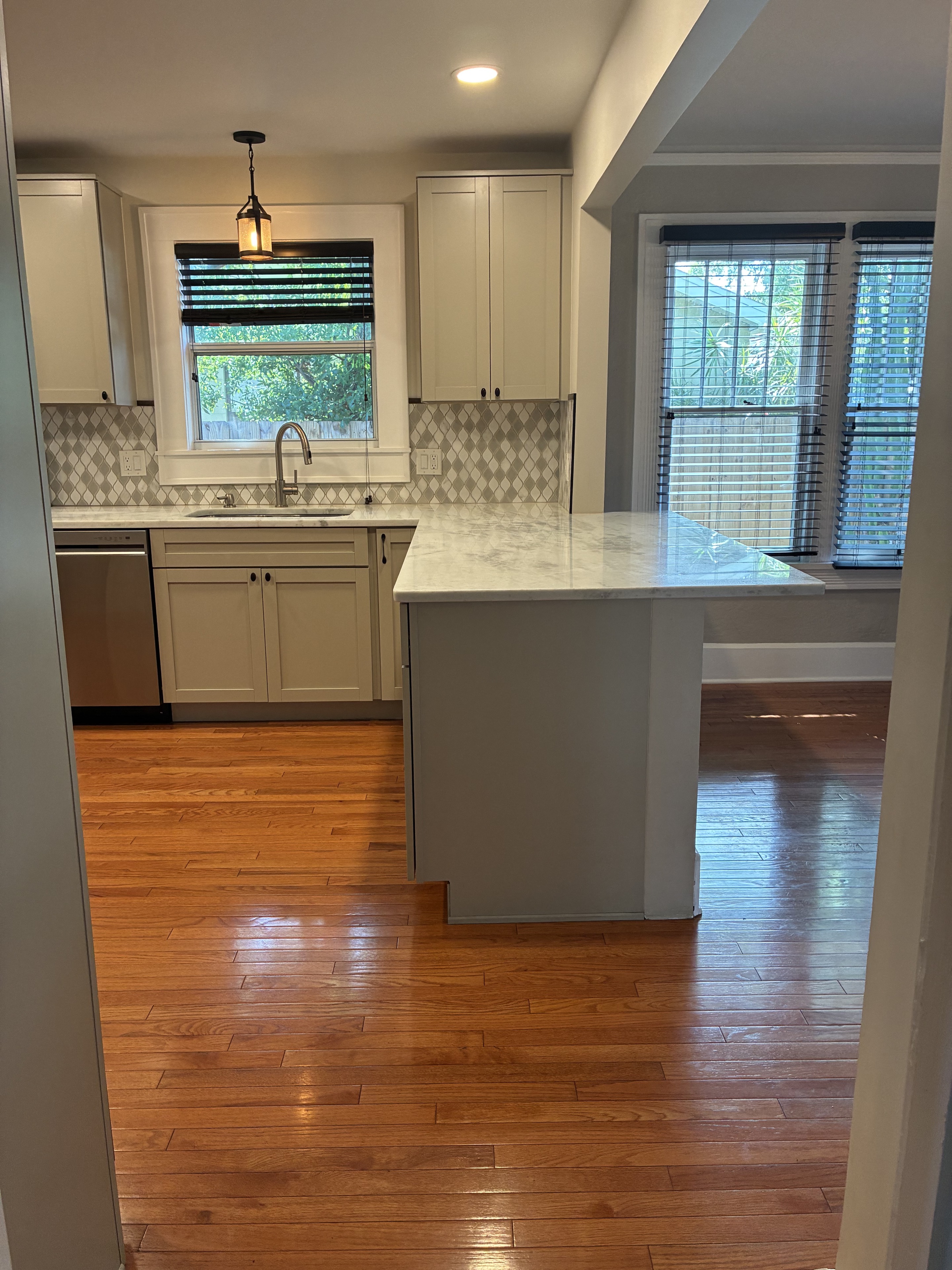 Clean kitchen entry with bright counters and polished hardwood floor