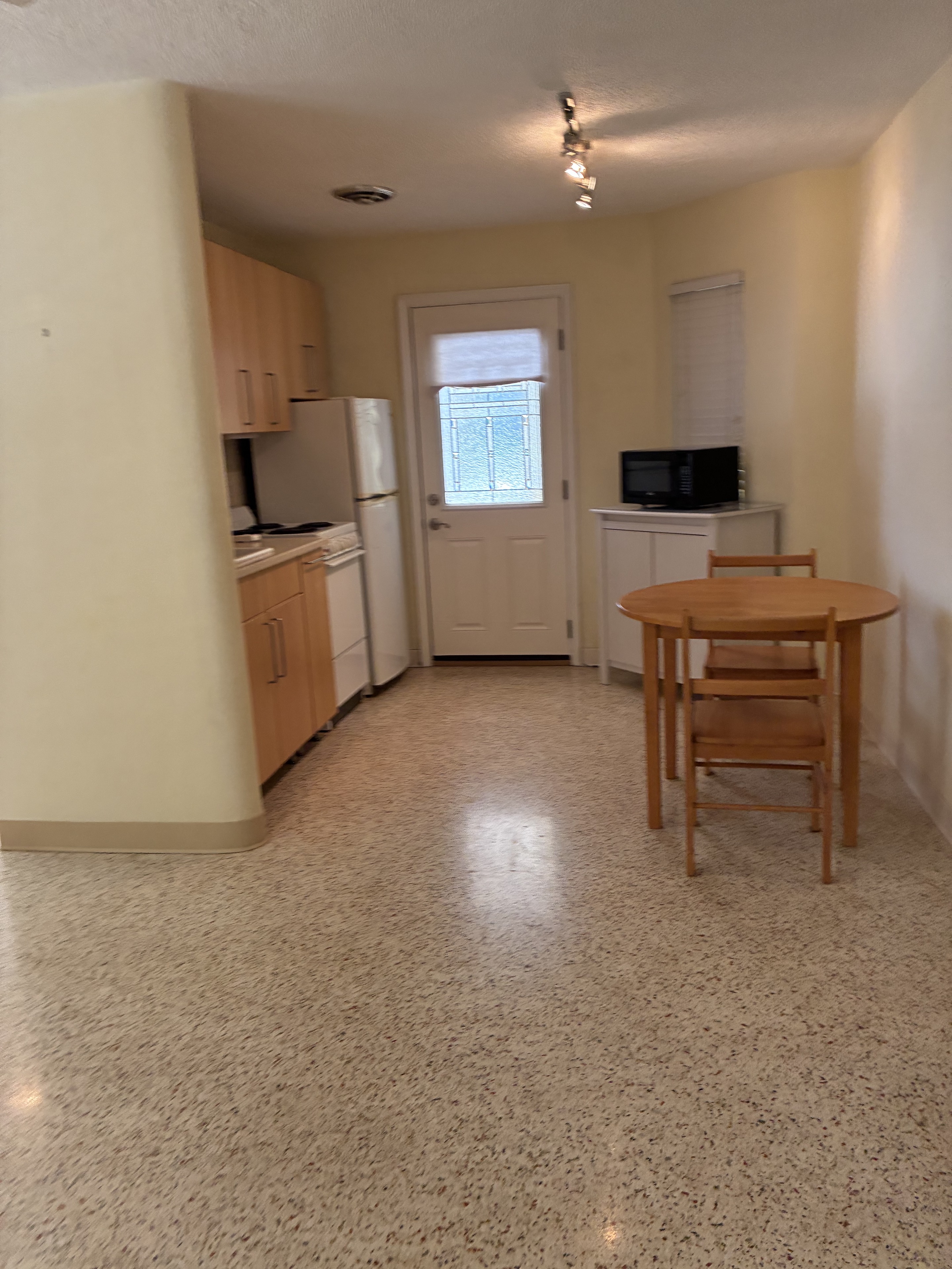 Clean kitchenette with table, refrigerator, and terrazzo floor