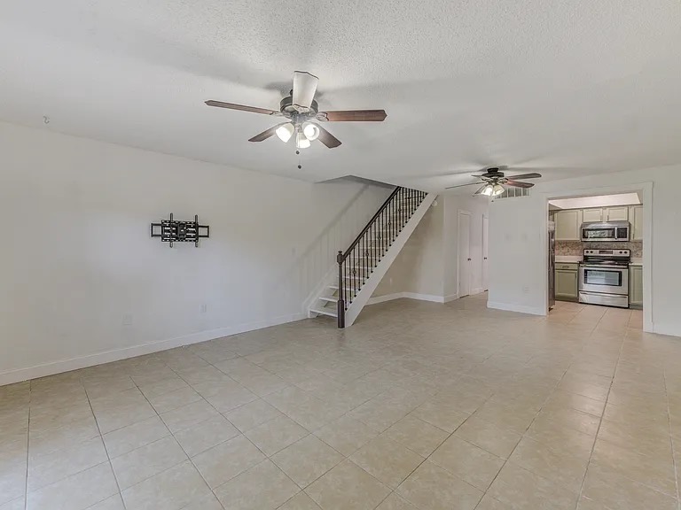 Clean empty living room with tile floors and staircase