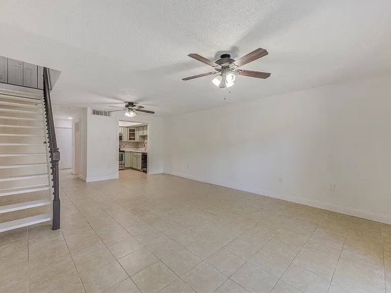 Clean open living room with staircase and tiled floor
