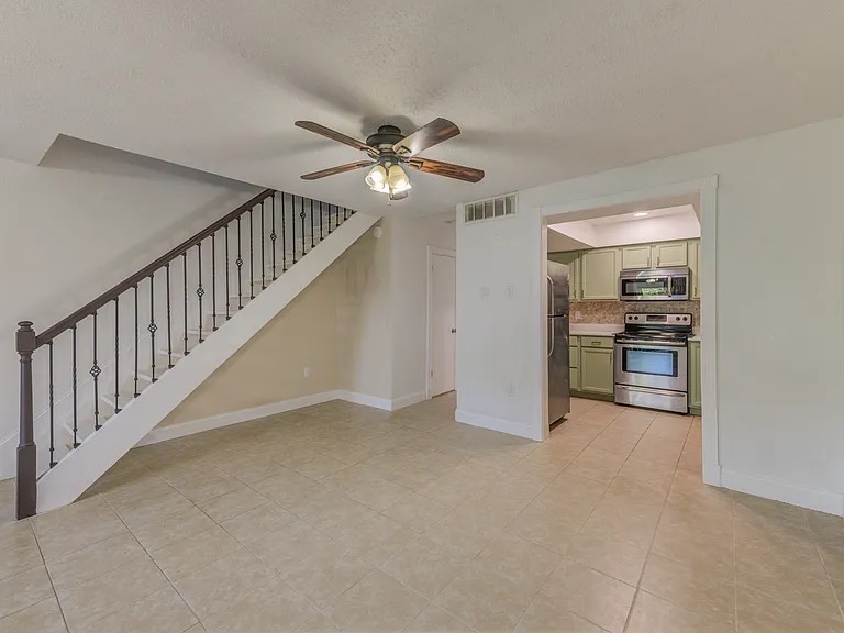Clean living area with staircase and kitchen entrance