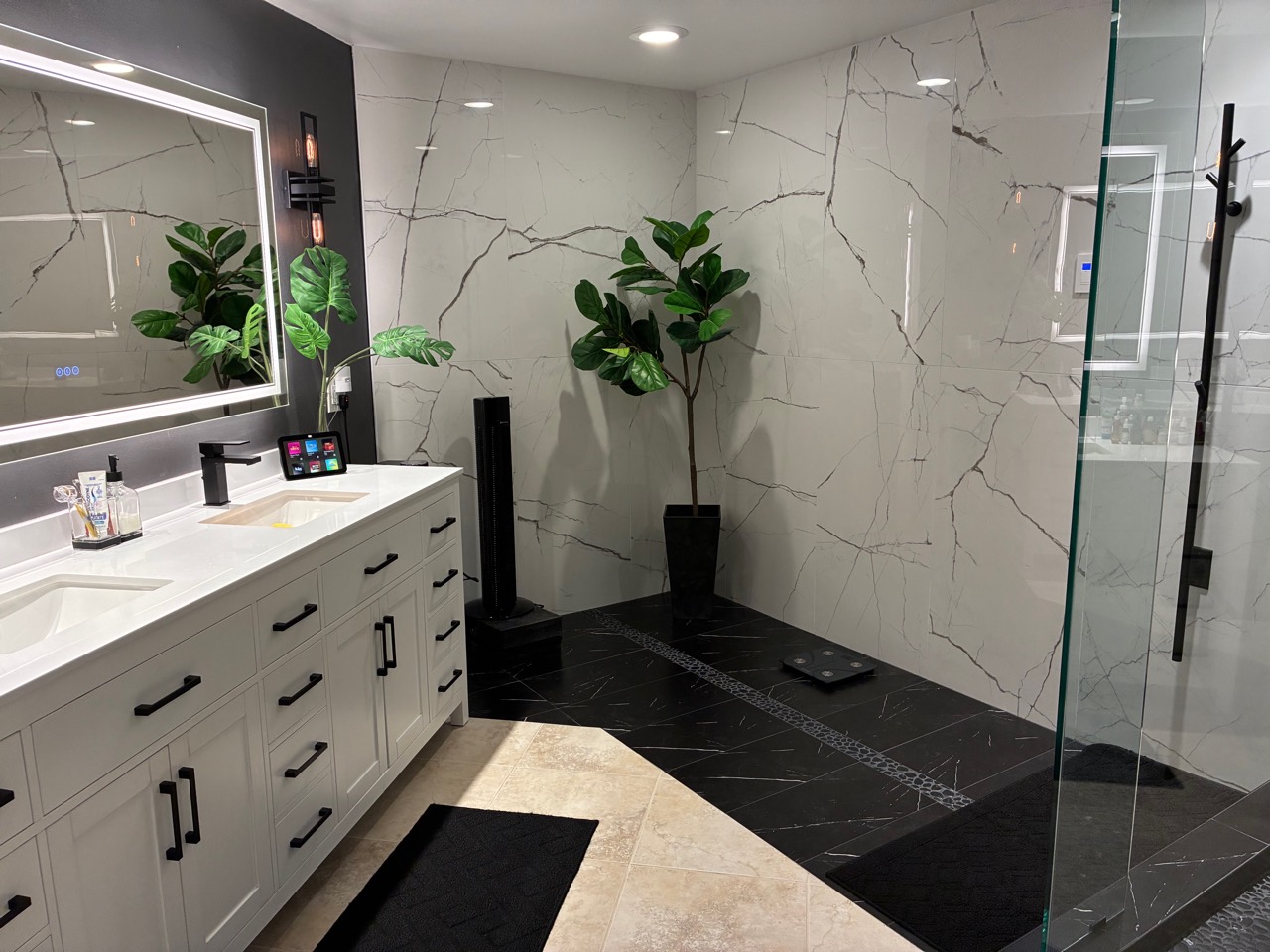 Clean luxury bathroom with double vanity, tile walls, and glass shower