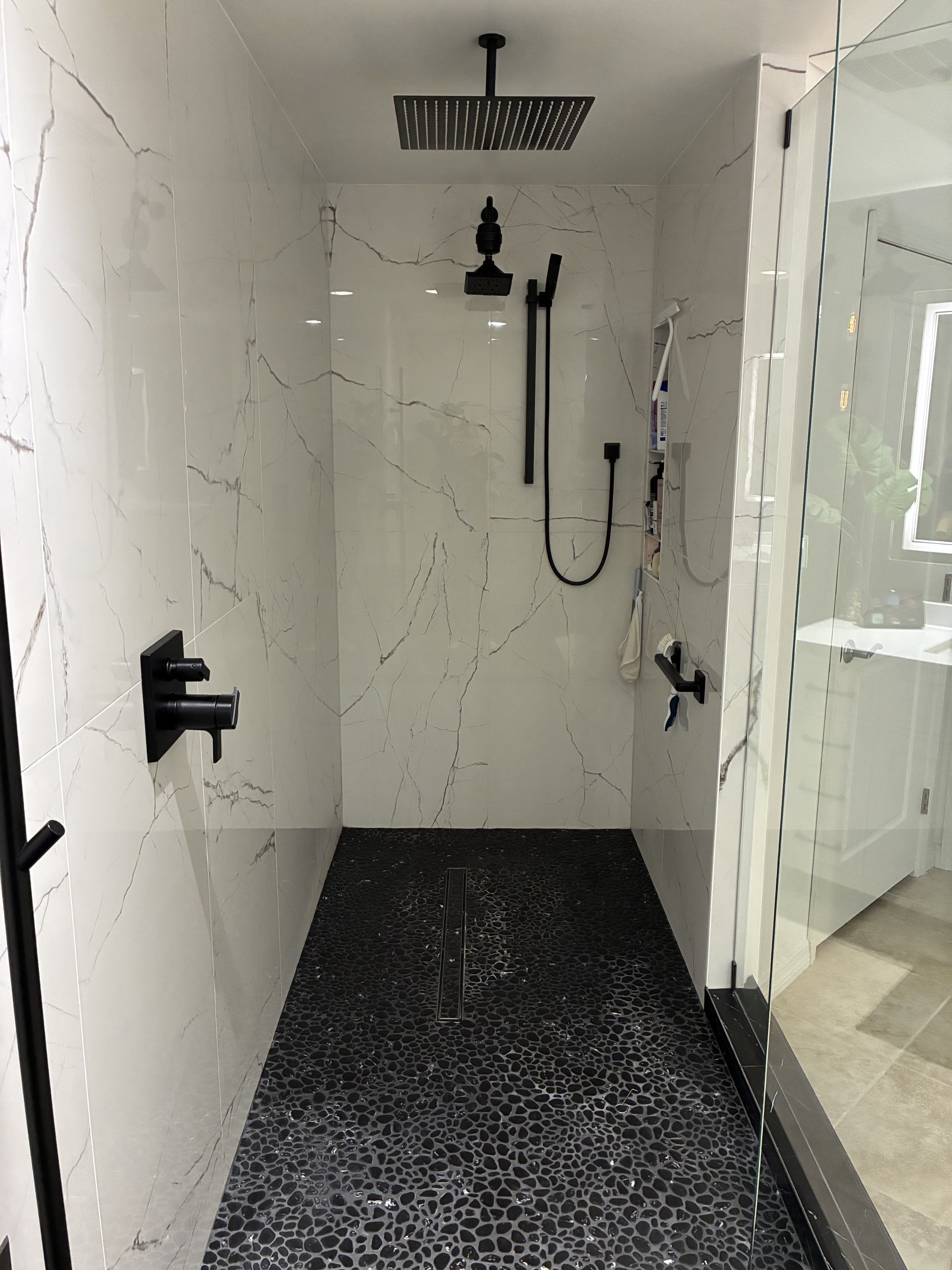 Clean marble-look shower with black fixtures and glass door