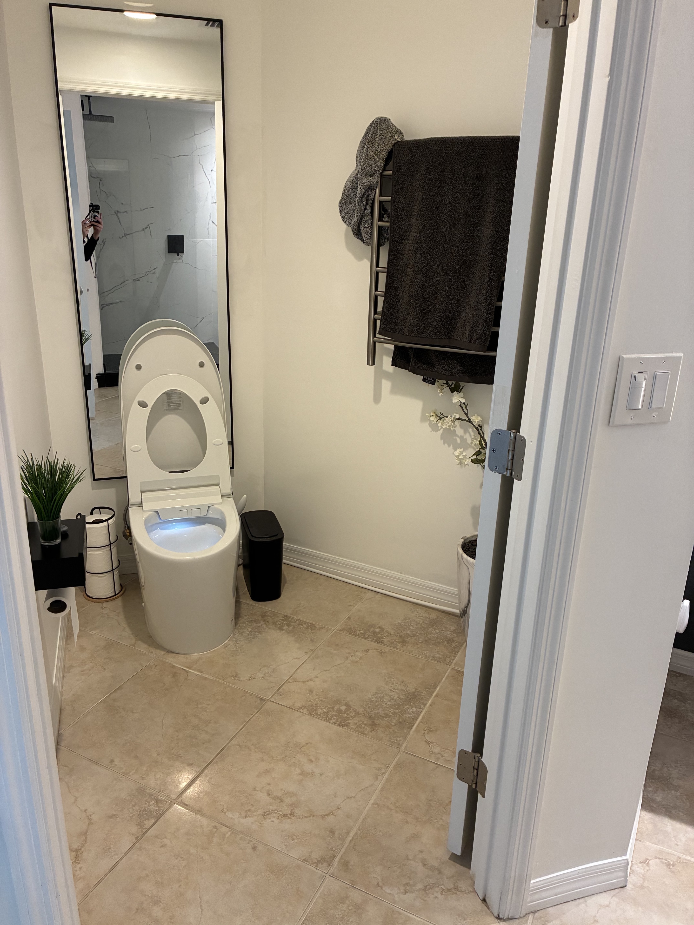 Clean powder room with toilet, mirror, tile floor, and towel rack