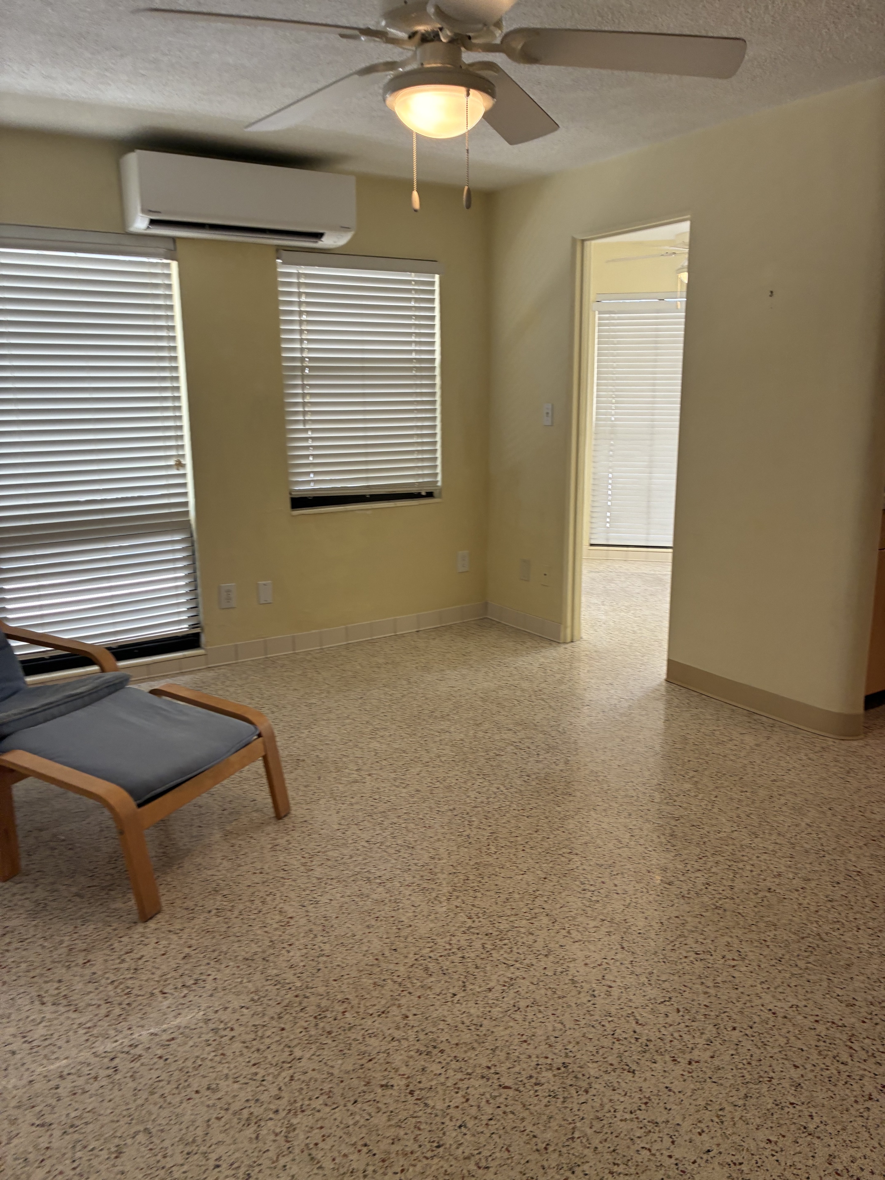Clean room with terrazzo floor, blinds, ceiling fan, and chair