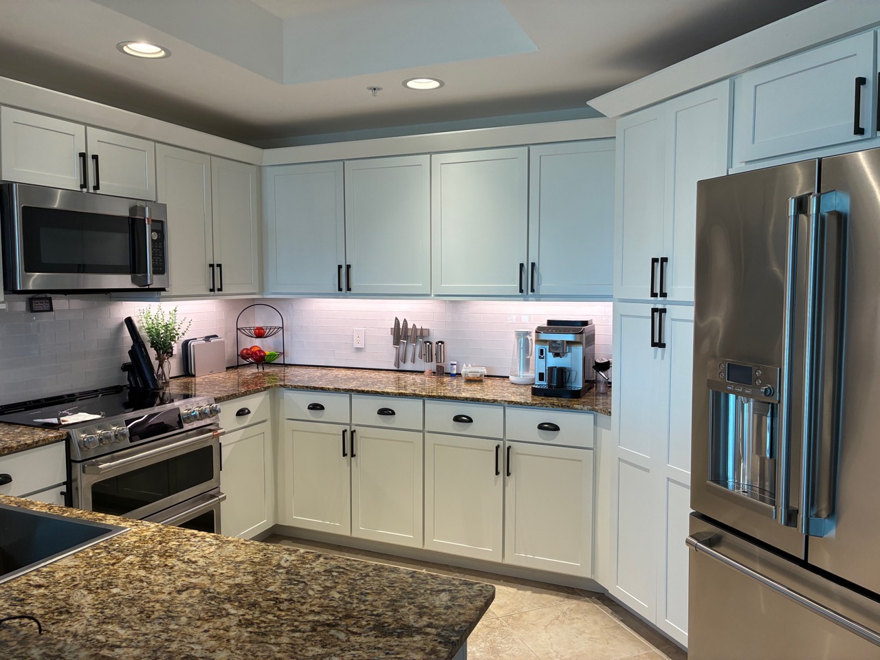 Clean white kitchen cabinets, granite counters, and stainless appliances